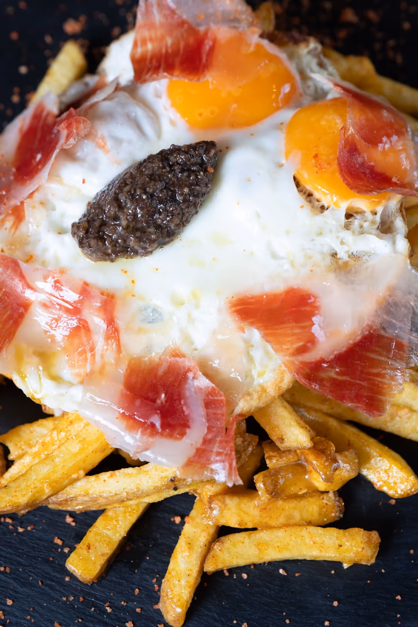 Huevos rotos con yema trufada y jamón ibérico